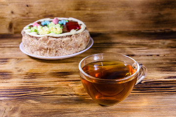Cup of tea and Kiev cake with cream, nuts and meringue on a wooden table
