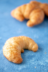 Flacky crispy fresh croissant rolls with blue background