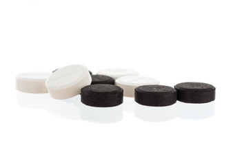 black round pills on a white background, white pills on a black background