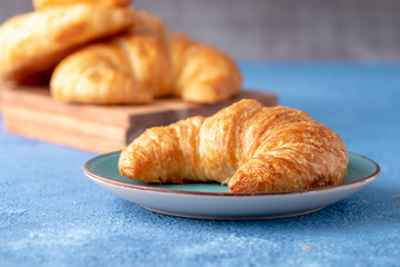 Flacky crispy fresh croissant rolls with blue background