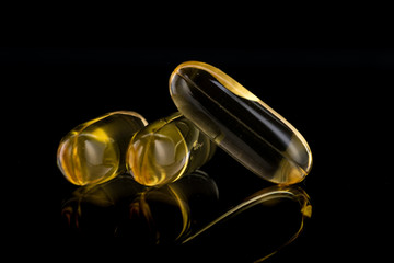 yellow oval long capsules with medicine on a black background