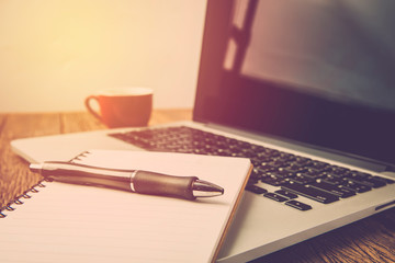 laptop and cup of coffee on wooden table with notebook