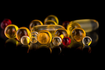 transparent white, yellow and red round medicine capsules and pills on a black and white background