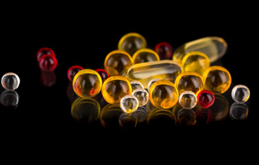 transparent white, yellow and red round medicine capsules and pills on a black and white background
