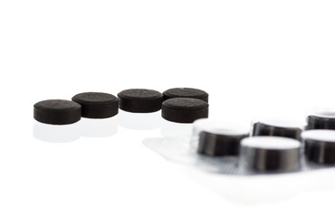 black round tablets of activated carbon on a white background