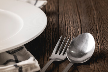 Empty white dinner plate and fork and spoon close up