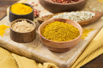 Curry powder in a wooden bowl on a wooden table. Variety of spices