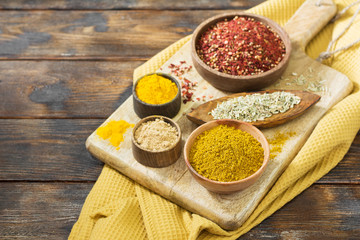 A variety of spices in wooden bowls on a wooden table. Traditional cuisine. Place for text