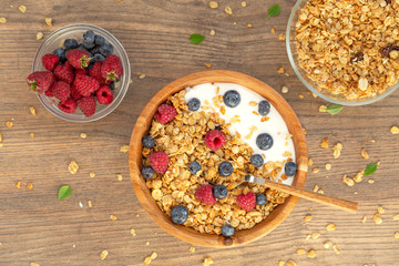 Yogurt with granola and berries fresh raspberries and blueberries on wooden background. Top view. Delicious and healthy Breakfast smoothie. Vegetarian food.