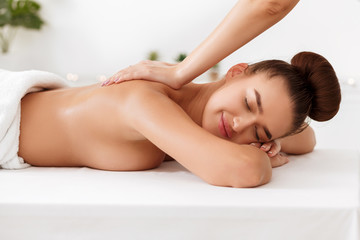 Masseur doing back massage to young woman in spa salon