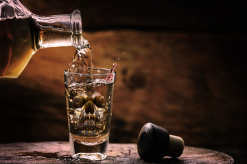 Drink bottle and glass with alcohol content. Image of translucent skull in glass. Alcoholism,...