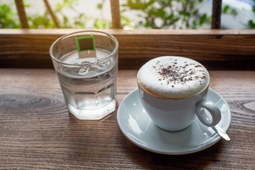 Cup of hot cappuccino coffee on wooden table