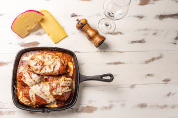 Parmegiana Steak also known as Filet Parmegiana in a black iron pan on a wooden white background, cheese and tomato sauce. Soft light, top view. Flat layer