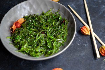 Seaweed Salad. Dietary and very beneficial for the thyroid gland. Dressed with vegetable oil, sprinkled with sesame seeds. Near wooden chopsticks. 