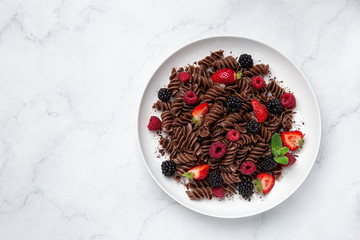 Sweet chocolate fusilli pasta with fresh berry on white plate