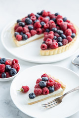 slice of blueberry  and raspberry tart  on white marble background