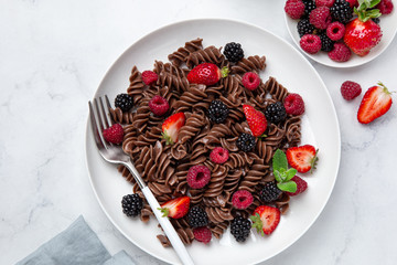 Sweet chocolate fusilli pasta with fresh berry on white plate