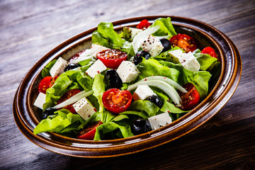 Greek salad in bowl on wooden table