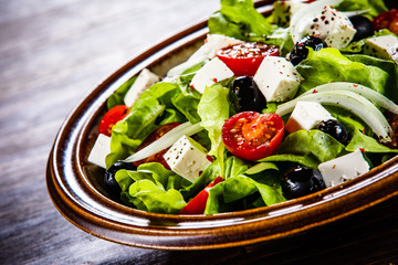Greek salad in bowl on wooden table