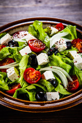 Greek salad in bowl on wooden table