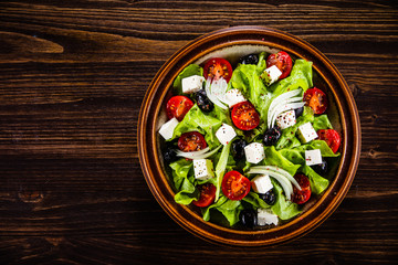 Greek salad in bowl on wooden table