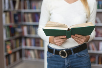 Caucasian girl with open book standing in library