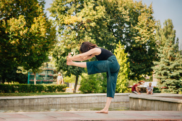 Fototapeta premium young girl in the park is doing yoga asana