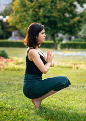 Naklejka na ściany i meble young girl in the park is doing yoga asana