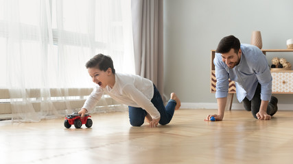 Funny dad and excited kid son racing cars at home
