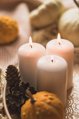 autumn cosy pumpkin, candles and autumn plants on window with led lights bokeh