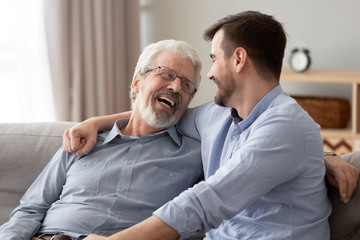 Obraz premium Happy two generations male family laugh talking bonding on sofa