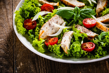 Caesar salad on white plate on wooden table