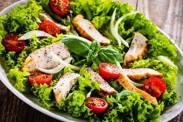 Caesar salad on white plate on wooden table