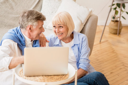 Happy Senior Couple Surfing Net On Laptop At Home