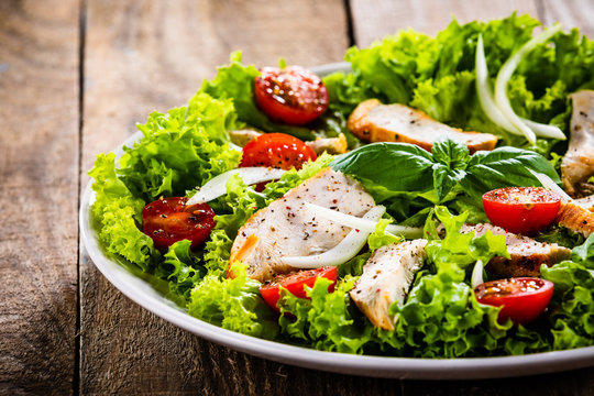 Caesar salad on white plate on wooden table