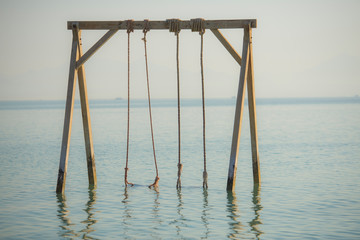 Wooden swing in shallow water on tropical beach