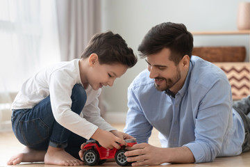 Happy dad and kid son play toy car at home