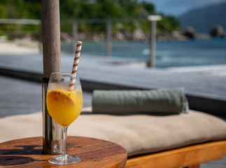 glass of orange juice on wooden table on the beach