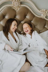 Mom and daughter are fighting pillows on the bed, pillow fight