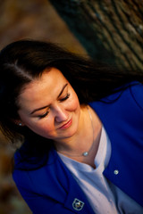 Golden autumn. Beautiful brunette caucasian woman in a blue cardigan in the city park at sunset. Plus-size model.