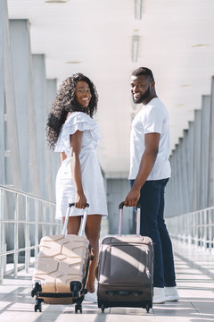 Cheerful african american couple walking in airport with luggage