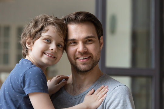 Young smiling father holding little preschool son on hands.