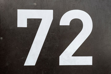 Number 72, seventy-two, street number sign on the wall	