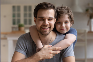 Happy little cute boy hugging smiling young father.