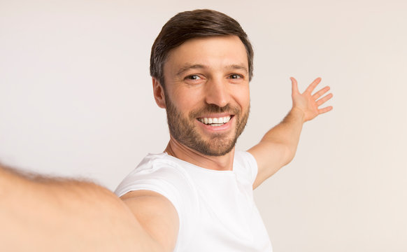 Man Taking Selfie Showing Something Behind Him, White Background