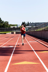 Young Hispanic Woman Running On Track Blue Shorts Red Top