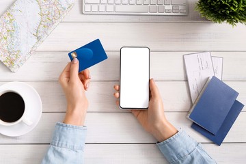 Woman using smartphone and credit card for booking hotel.