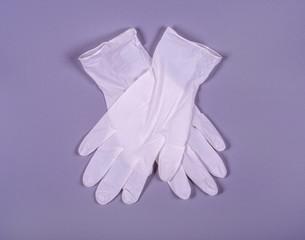 A pair of white medical gloves on a gray background