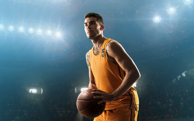 Young professional basketball player on floodlit court with the ball