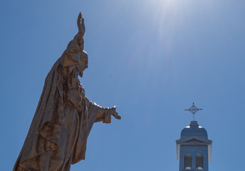 Statue of the Sacred Heart in front of a steeple